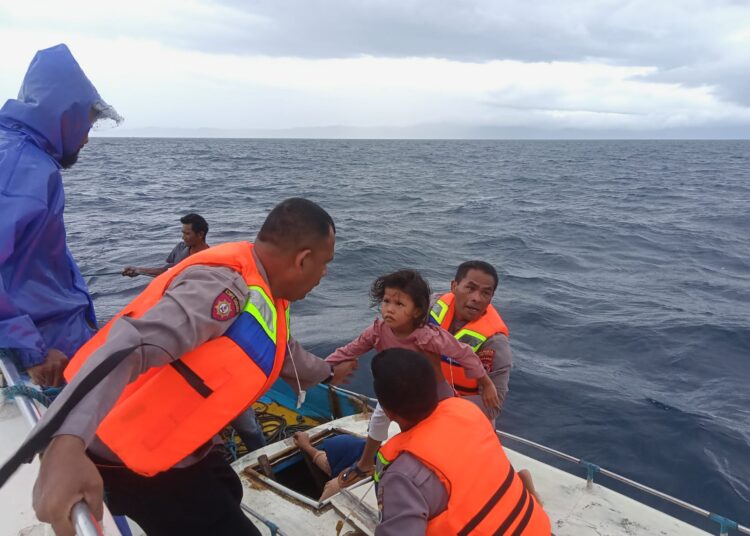 Kapolsek Leihitu Iptu Julkisno Kaisupy tampak sedang mengevakuasi seorang anak kecil dari speedboat Rikma yang mati mesin ke speedboat penyelamat Teluk Huamual Star di perairan antara Pulau Ambon dan Seram, Selasa (27/12/2021). (Foto: Istimewa)