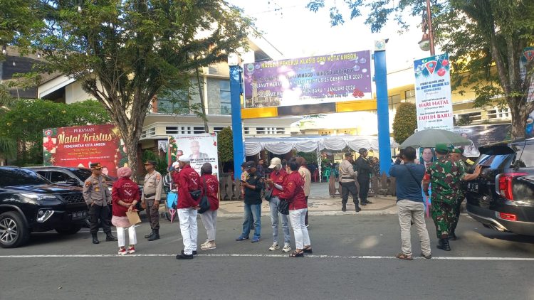 Tampak aparat kepolisian bersama komunitas Maluku Satu Rasa Salam Sarane melakukan penjagaan di depan pintu gereja Maranatha, Kota Ambon, Minggu (24/12/2023). Saat itu umat Kristen sementara melaksanakan ibadah. (FOTO: AMBONKITA.COM)