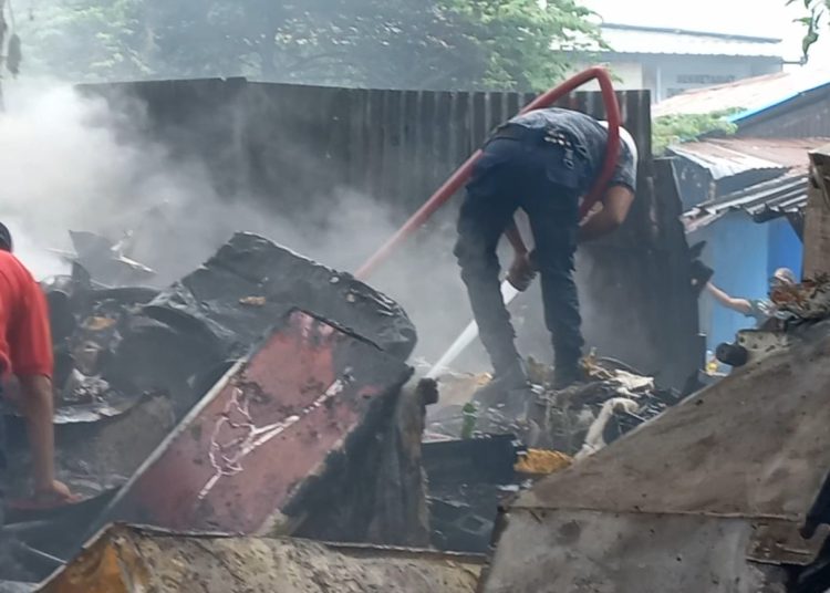 Petugas Damkar Kota Ambon tampak sedang melakukan penyemprotan air pada bara api yang masih nyala di gudang besi tua di Talake, Kota Ambon, Jumat (27/12/2024). (Foto: Husen Toisuta/Ambonkita.com)