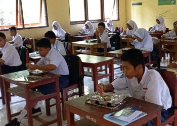 Para siswa SMPN 16 Ambon tampak menikmati program makan bergizi gratis di dalam ruangan kelas, Selasa (22/1/2024). (Foto: Husen Toisuta/Ambonkita.com)